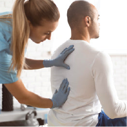 A physical therapist placing her hands on a patient's back