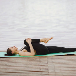 A woman lying on her back stretching her piriformis muscle