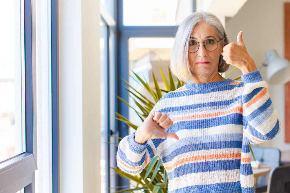 An elderly woman with a thumb up and down