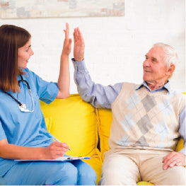 A caregiver and elderly man high-fiving