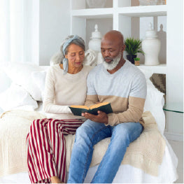 A senior couple at home reading a book together