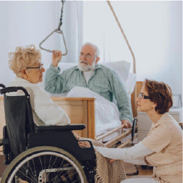 A caregiver helping an elderly man and woman in a nursing home