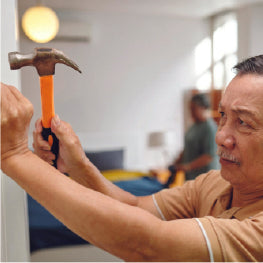 An elderly man hammering a wall