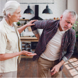 An elderly woman comforting a man with back pain