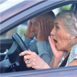 A senior couple looking scared in a car