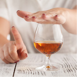A person covering alcohol in a glass while shaking their finger