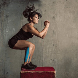 A woman jumping on a box with kinesiology tape on her leg