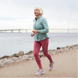 An elderly woman running in front of water