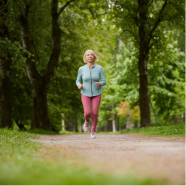 An elderly woman running outside in a forest
