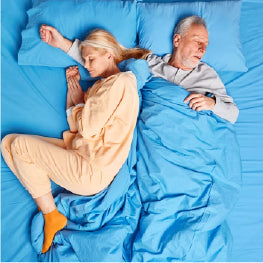 An elderly couple sleeping in bed