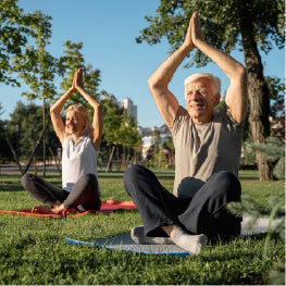 Two elderly people stretching on a yoga mat