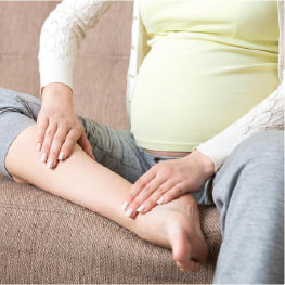 A pregnant woman holding her leg in pain