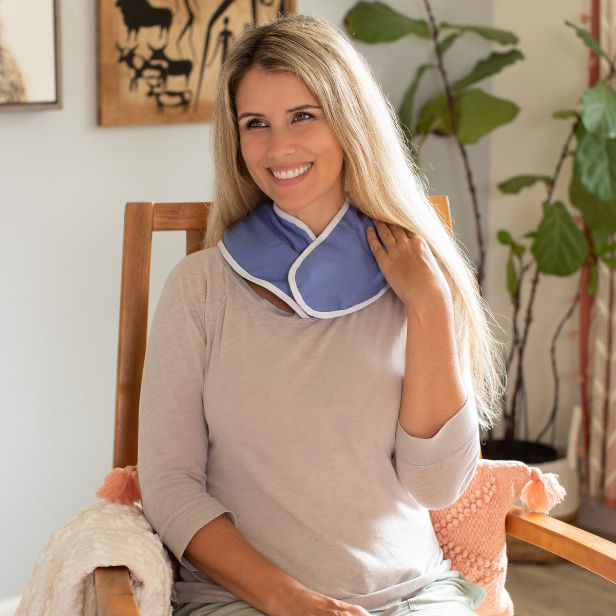 A woman sitting in a rocking chair with the ThermiPaq neck wrap around her neck.