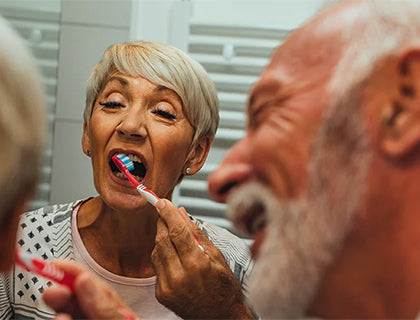 An elderly couple brushing their teeth