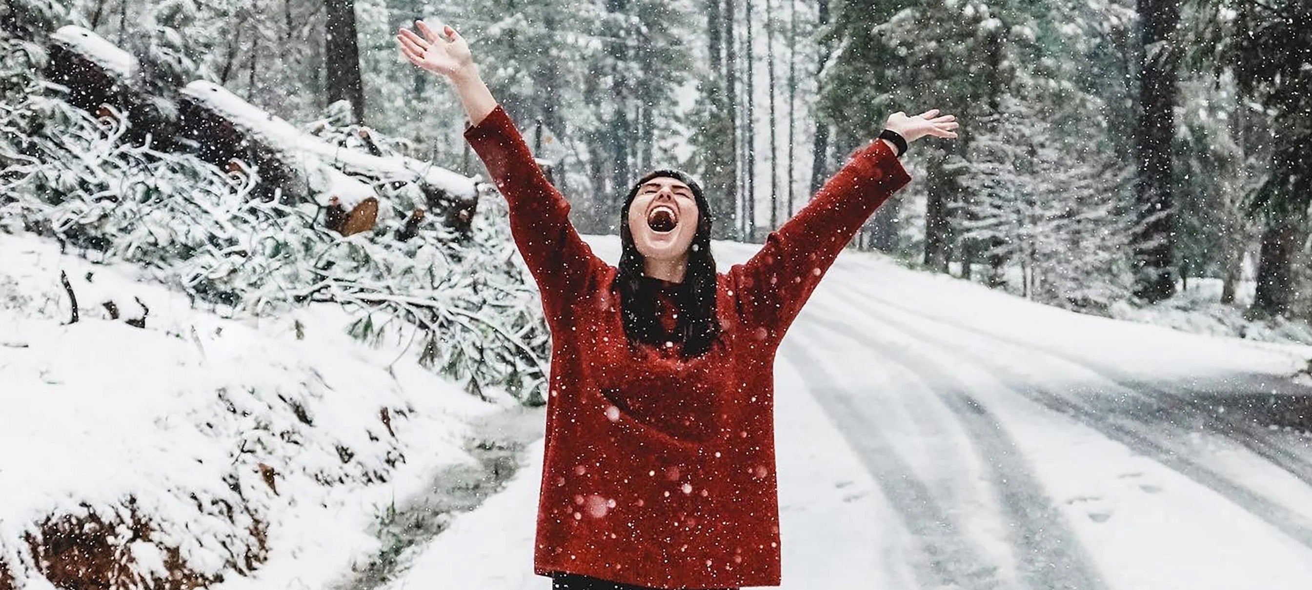 A woman holding her hands up in joy surrounded by snow