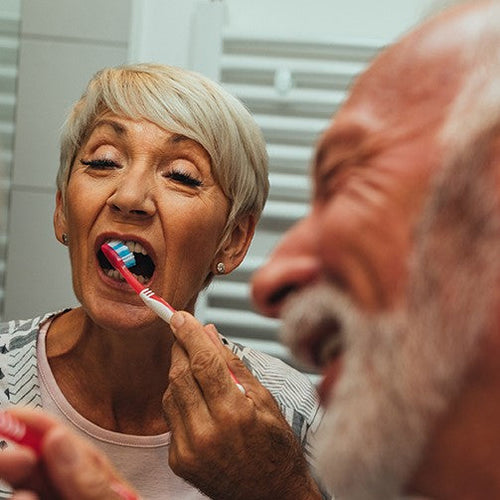 An elderly couple brushing their teeth