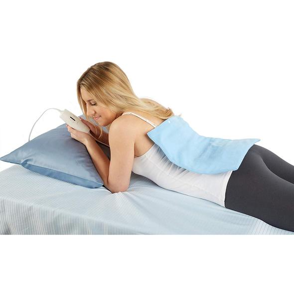 A woman lying on her stomach with the TheraMed heating pad over her back