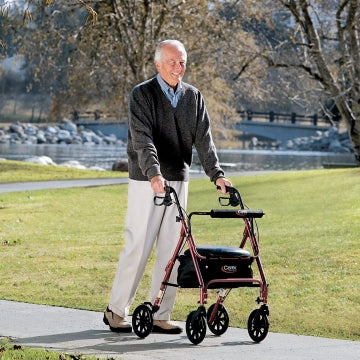 An elderly man walking with the Carex Rolling Walker in a park 