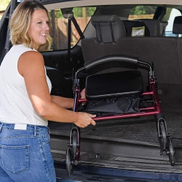 A woman placing the ProBasics Aluminum Rollator into her car trunk