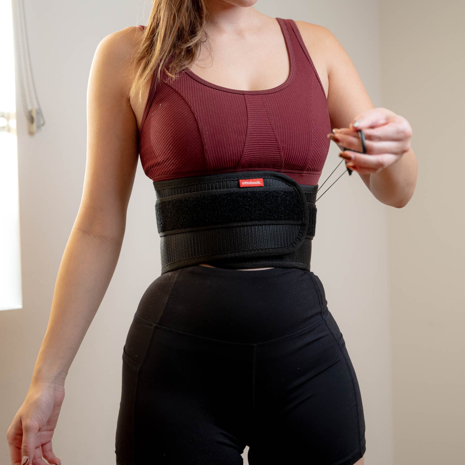 A woman adjusting a back brace on her lower back