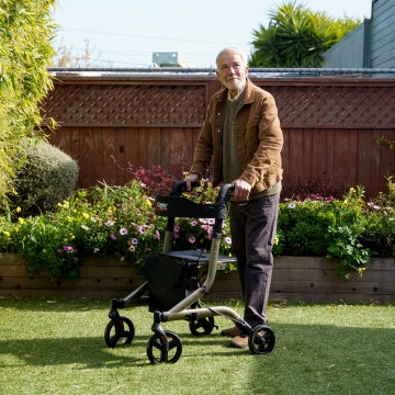 A man standing outside on grass with the Carex Crosstour Rolling Walker 