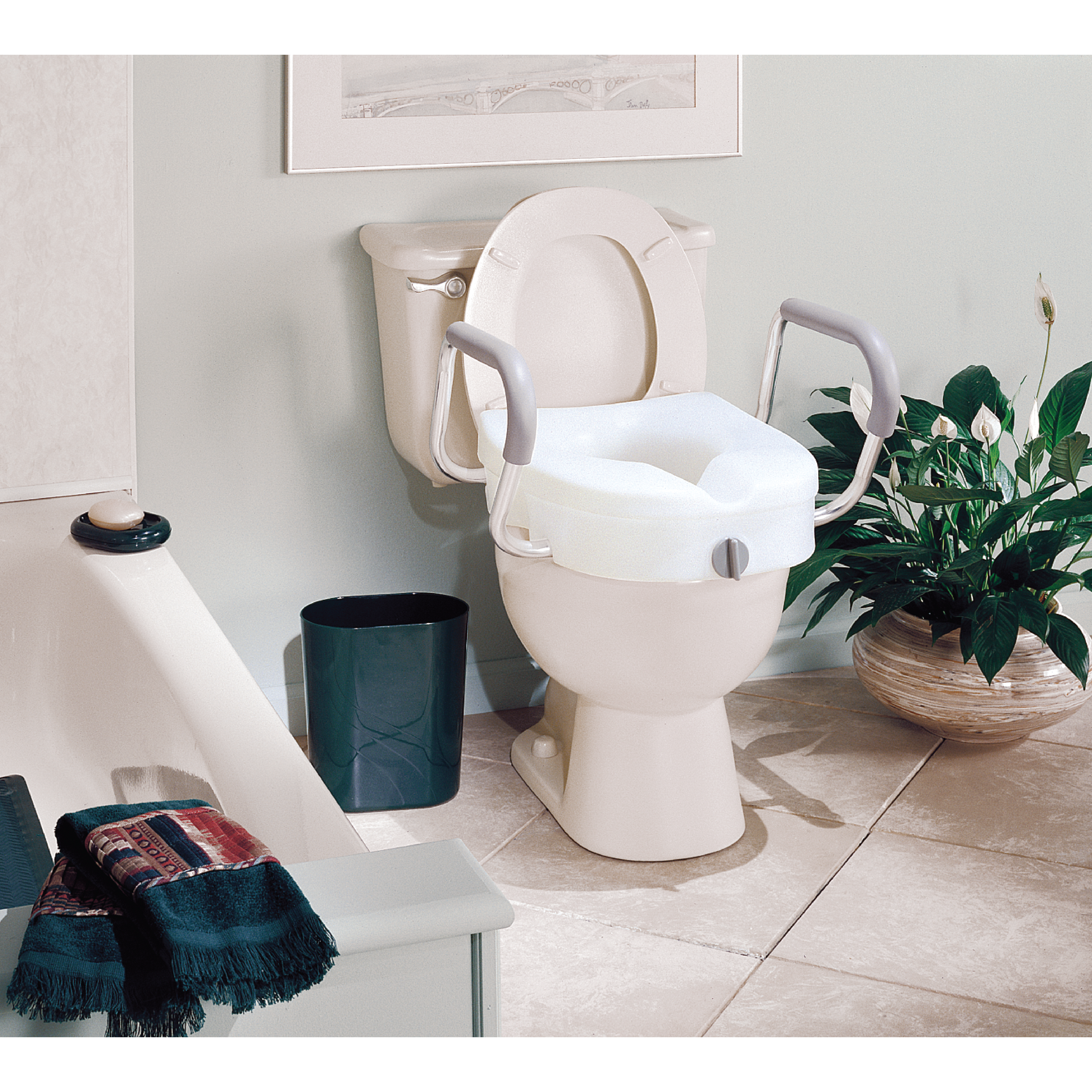 A raised toilet seat with armrests on a toilet