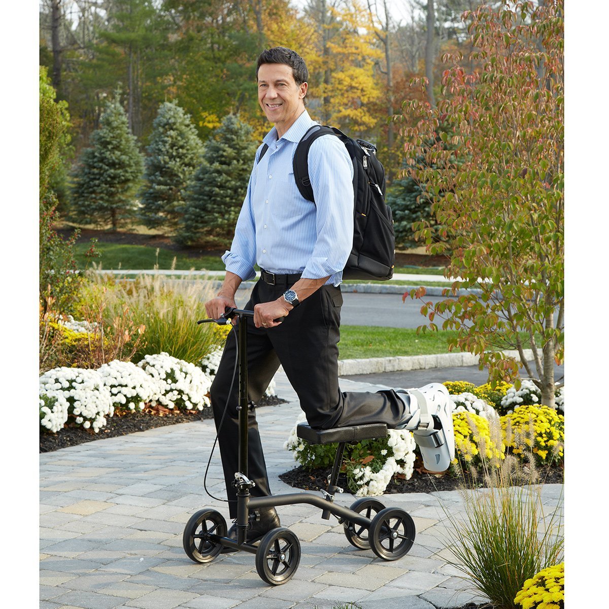 A man in a park on a knee scooter