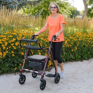 A woman in a park with the ProBasics Aluminum Transport Rollator