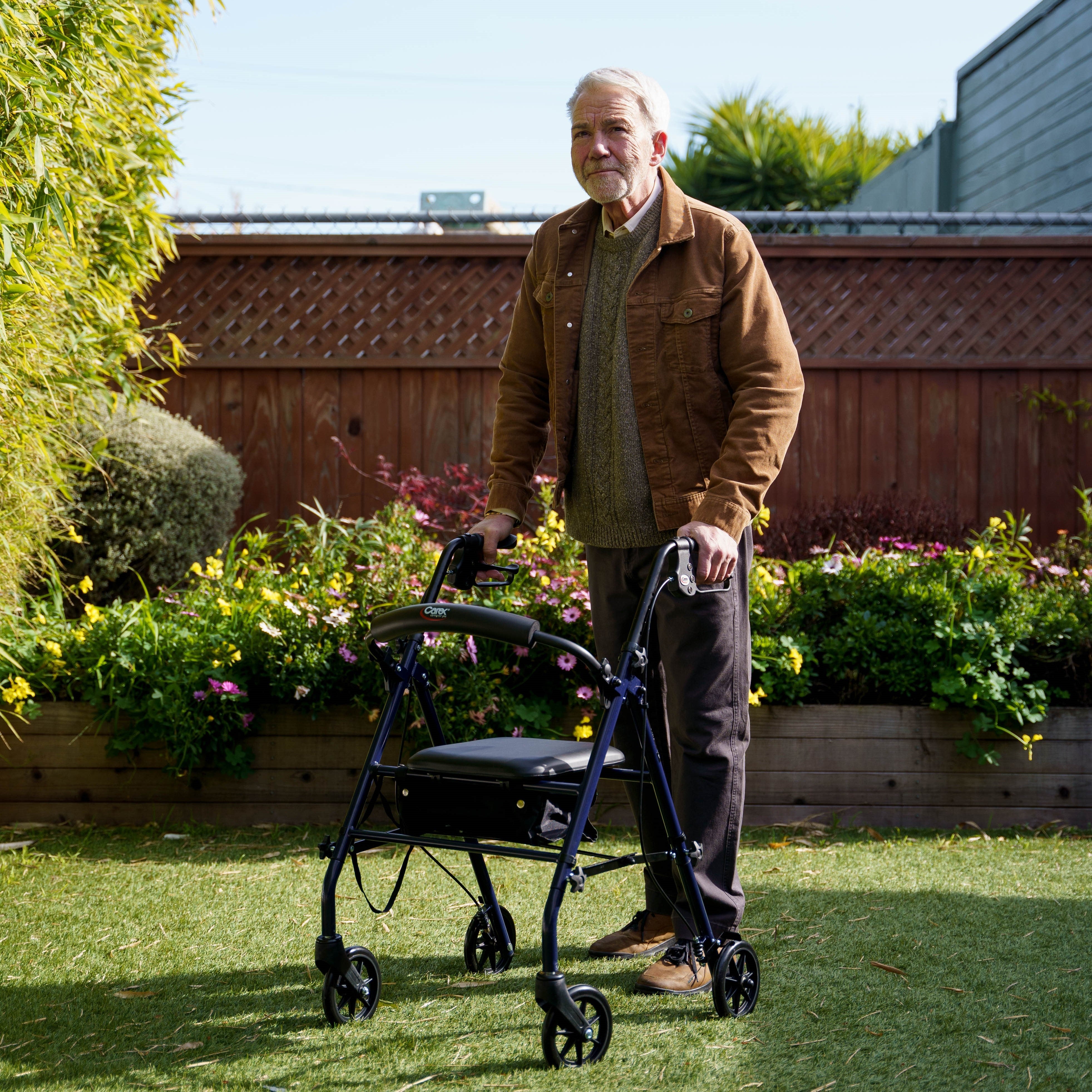 An elderly man using a rollator on grass
