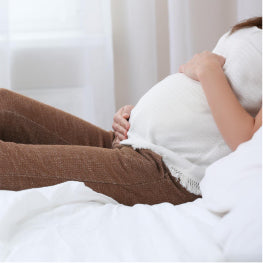 A pregnant woman sitting down holding her stomach
