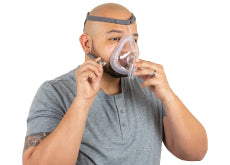 A man putting on a full face CPAP Mask