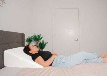 A woman in bed on her back on a wedge pillow