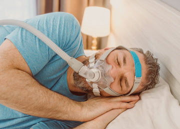 A man sleeping on his side with a CPAP mask on