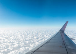 The wing of a plane in a blue sky with clouds