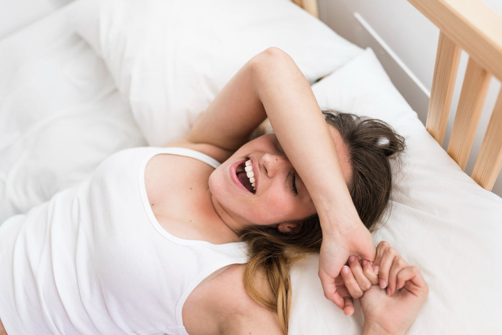 A smiling woman waking up in bed