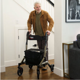 An elderly man walking inside with a rollator