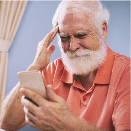 An elderly man struggling to use a phone