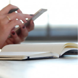 A hand holding a phone in front of a journal