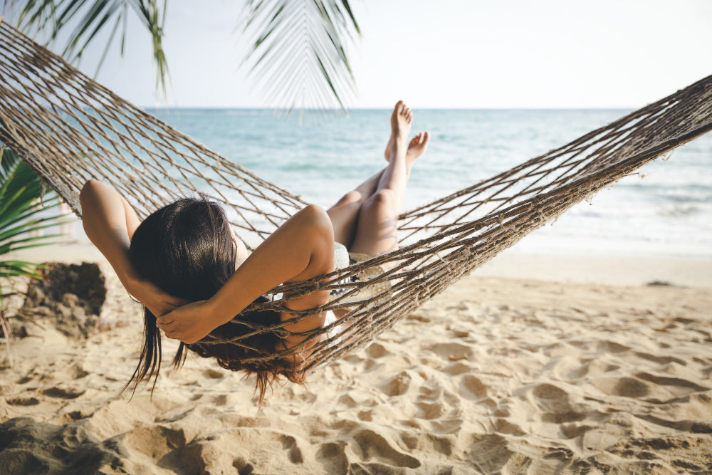 A woman in a hammock in sunlight on a beach