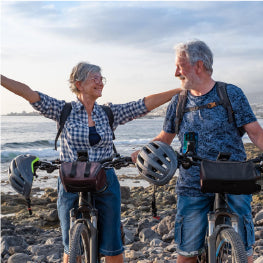 An elderly couple riding bikes at the beach