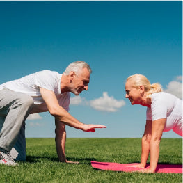 An elderly man encouraging a woman to do a push up on a yoga mat