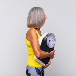 An elderly woman holding a weight scale