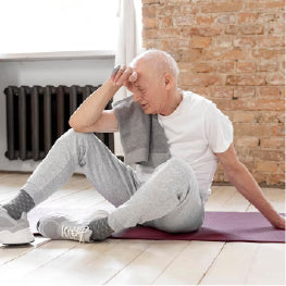 An elderly man tired on a yoga mat