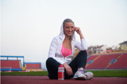 A woman sitting on a running track in a stadium