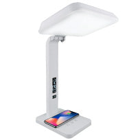 A white therapy lamp with a squar head and cell phone charging on it.