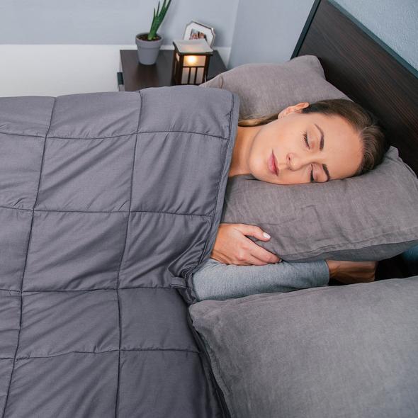 A woman sleeping with the Bed Buddy Weighted Blanket over her