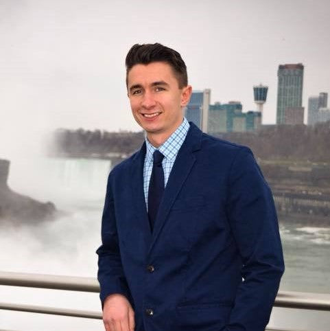 A person in a suit standing in front of a waterfall
