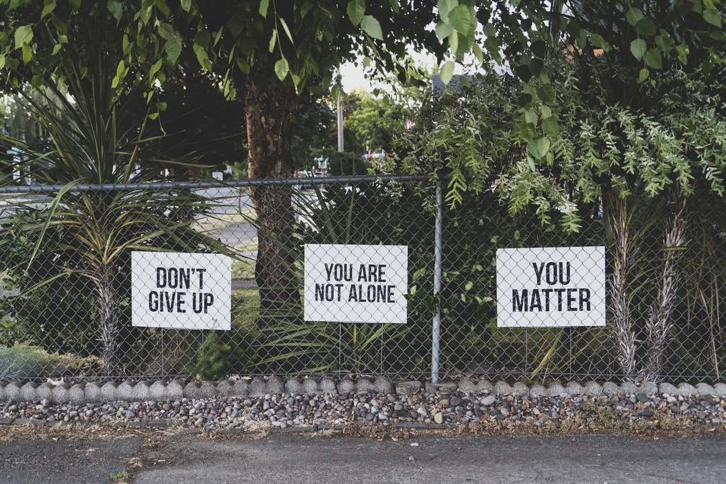 A fence with various encouraging signs on it