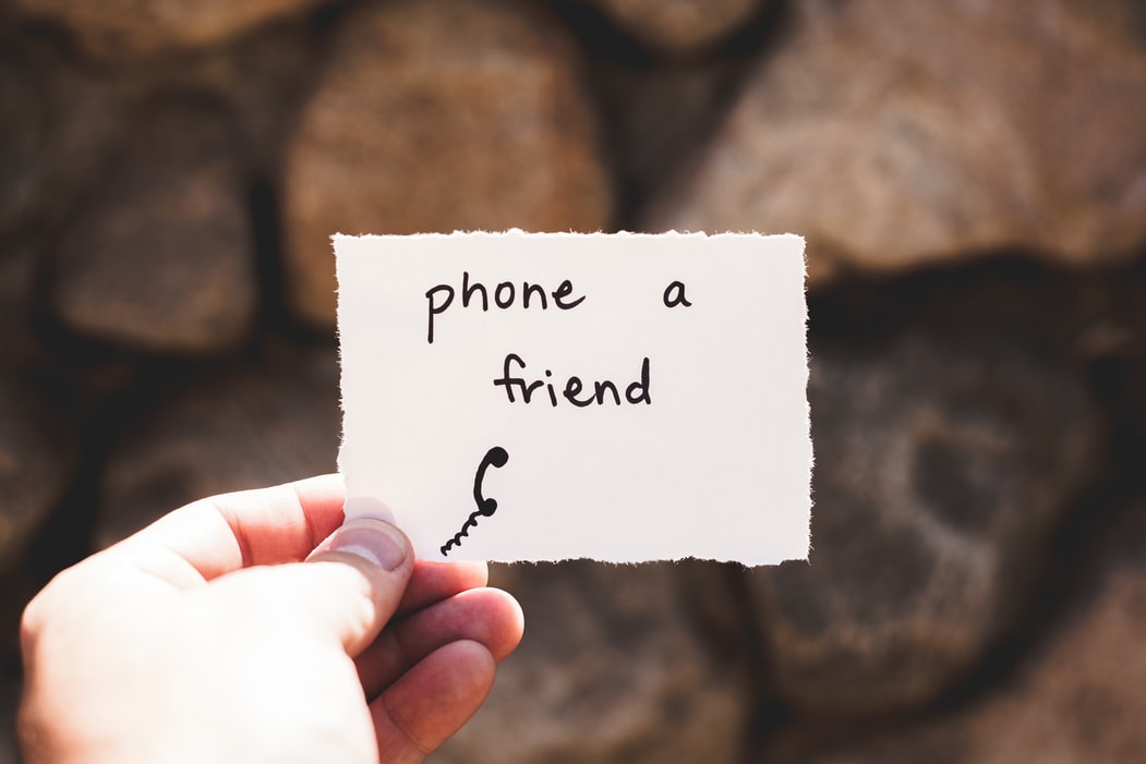 A person holding a sign that says phone a friend with a phone drawing below it