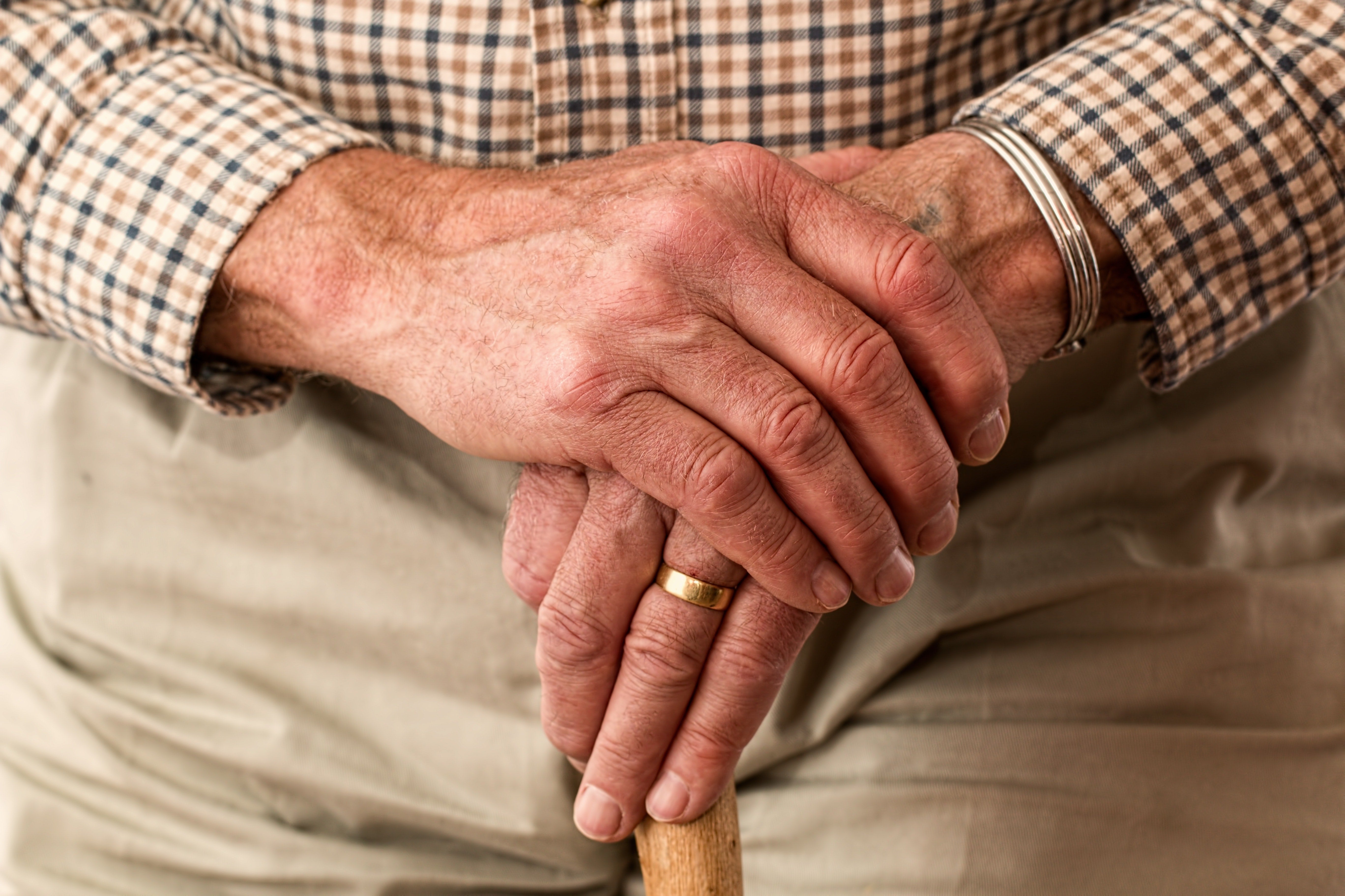 Close up of an elderly man's hands holding a walking cane